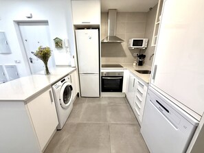 A modern kitchen with a built-in washing machine, a refrigerator, an oven, and a microwave. - SR Playa de los Boliches 2-Bedroom Apartment, Downtown Fuengirola (Fuengirola)