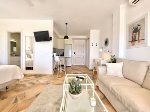 Una sala de estar moderna con un sofá, una mesa de centro con una planta y un televisor montado en la pared.