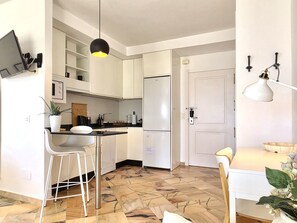 A modern kitchen with white cabinets, a stainless steel refrigerator, a bar counter with stools, and a pendant light. - SR Romana Playa 545 Studio with a Wonderful Ocean View (Marbella)