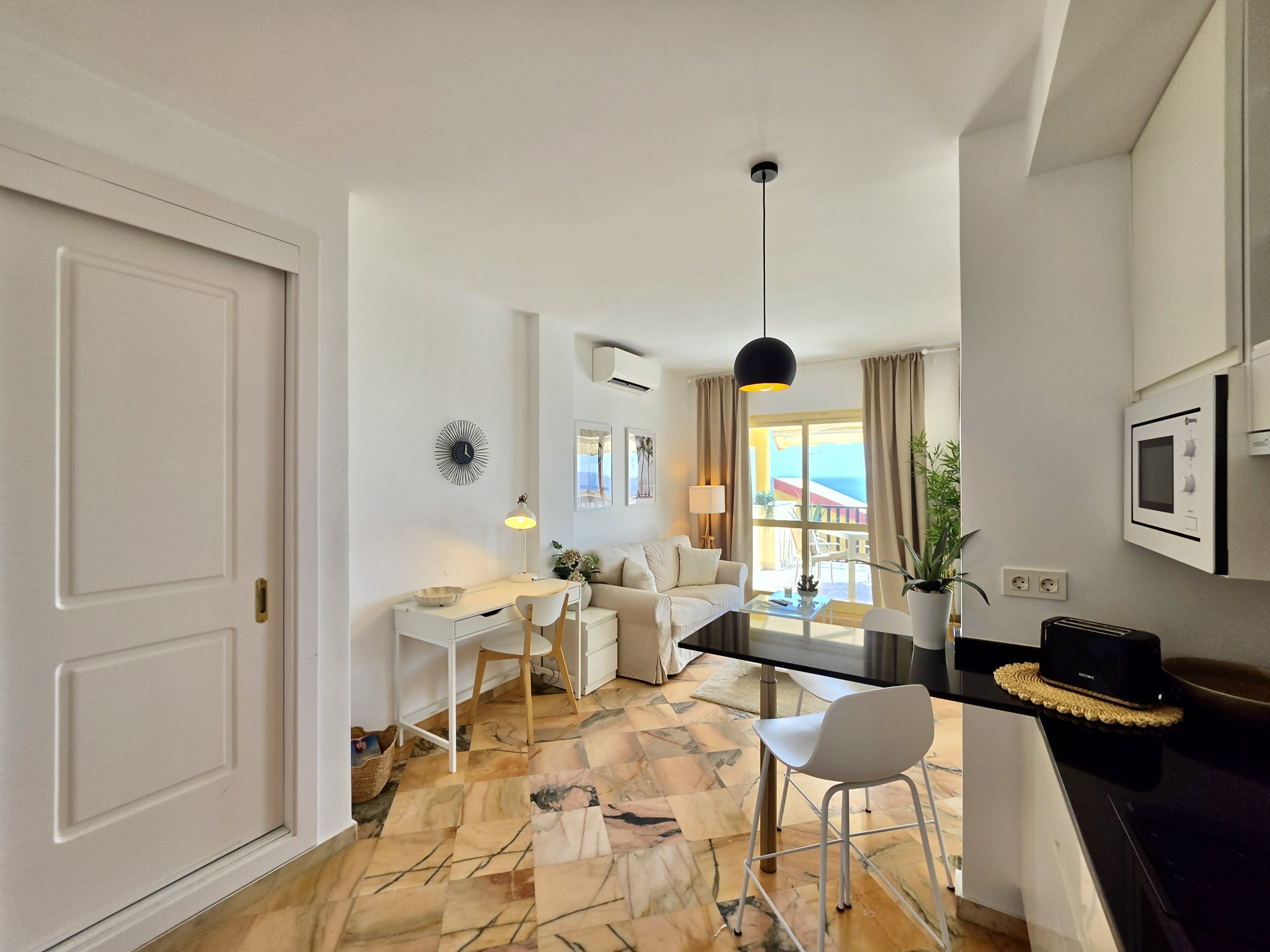 Un salon moderne comprenant un coin repas, un canapé, une table basse et un luminaire suspendu.