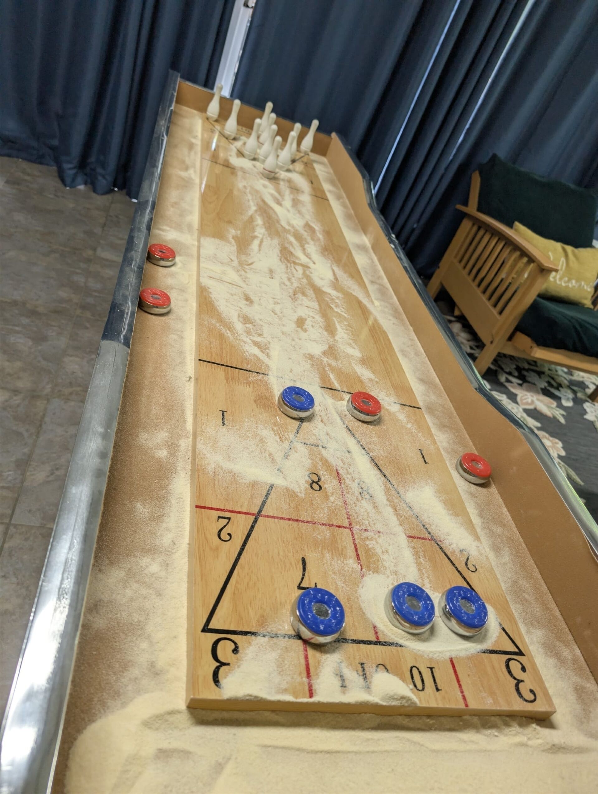 A shuffleboard table with numbered scoring areas and pucks.