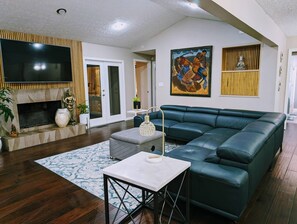 A modern living room with a sectional sofa, a flat-screen TV, a fireplace, and decorative items. - Colony Home for Family Groups - Patio, Workspace (Marietta)