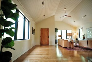 A spacious room with a wooden floor, a ceiling fan, and a large window. - Charming 4-bedroom MidCentury Bungalow—Brand New! (Oxford)
