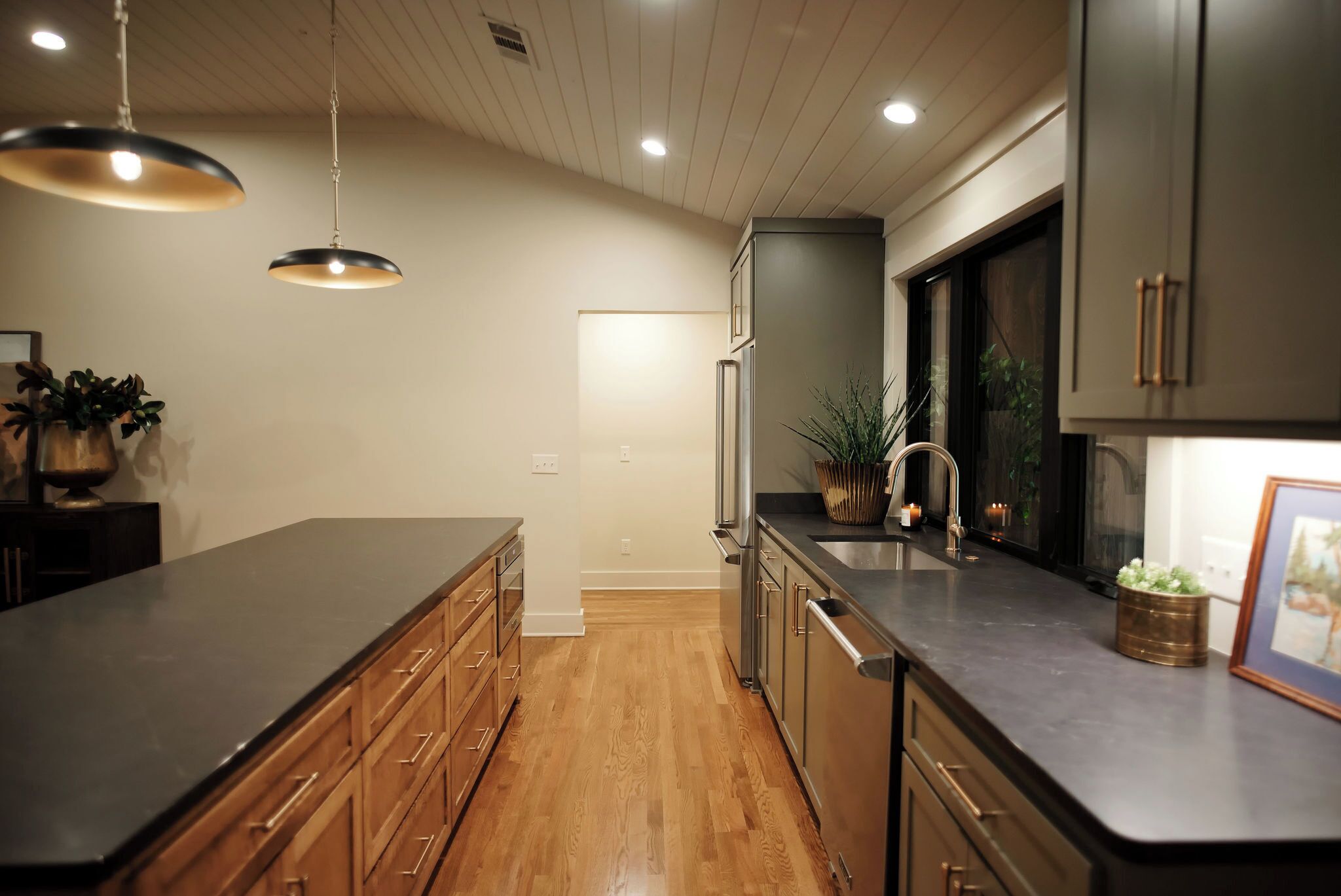 A modern kitchen with wooden cabinets, a stainless steel refrigerator, and a black countertop.