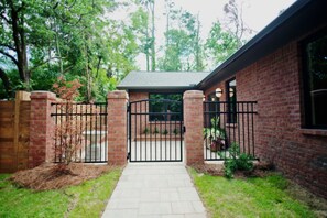A brick house with a gated entrance, a paved pathway, and a small garden area. - Charming 4-bedroom MidCentury Bungalow—Brand New! (Oxford)