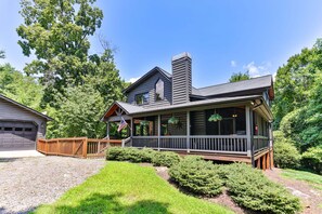 A two-story house with a porch, a garage, and a well-maintained lawn. - Chestnut Hills Lodge by Mountain Oasis | Luxury Blue Ridge Cabin (Blue Ridge)