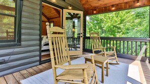 Eine Holzterrasse mit zwei Schaukelstühlen und einer Glastür, die zu einem Innenraum führt.