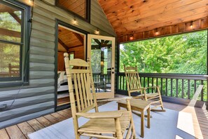 A wooden deck with two rocking chairs and a glass door leading to an interior space. - Chestnut Hills Lodge by Mountain Oasis | Luxury Blue Ridge Cabin (Blue Ridge)