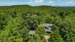 A house surrounded by dense forest with a clear view of the surrounding landscape. - Chestnut Hills Lodge by Mountain Oasis | Luxury Blue Ridge Cabin (Blue Ridge)