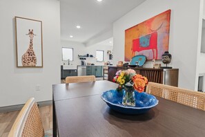 A dining area with a large table, chairs, and a vase with flowers. - Private pool, walk to downtown Springdale, dogs welcome, close to U of A. (Springdale)