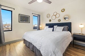 A bedroom with a bed, a ceiling fan, a nightstand, and wall decorations. - Private pool, walk to downtown Springdale, dogs welcome, close to U of A. (Springdale)