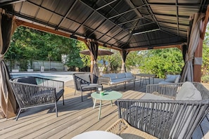 An outdoor patio with wicker furniture, a round table, and a covered area with a metal roof. - Private pool, walk to downtown Springdale, dogs welcome, close to U of A. (Springdale)