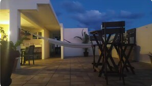 A patio area with a hammock, outdoor furniture, and a view of the interior of a building. - La Sirenita: 2-bed studio with rooftop lounge access minutes from 5 Avenida (Playa del Carmen)