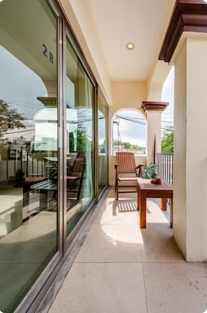 A balcony with a wooden table and chairs, a potted plant, and a view of the street. - La Sirenita: 2-bed studio with rooftop lounge access minutes from 5 Avenida (Playa del Carmen)