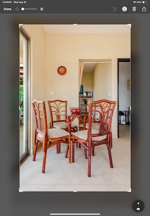 A dining area with a round table and four chairs, a bowl of fruit, and a wall-mounted decorative item. - La Sirenita: 2-bed studio with rooftop lounge access minutes from 5 Avenida (Playa del Carmen)