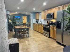 Una cocina moderna con gabinetes de madera, electrodomésticos de acero inoxidable y un comedor con mesa y sillas de madera.