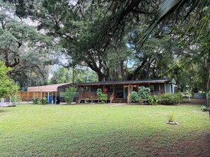 A rustic cabin with a porch, surrounded by a well-maintained lawn and large trees.