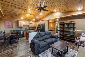 A cozy living room with a leather sofa, wooden coffee table, and a bookshelf.