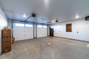 A garage with two white doors, a wooden door, and a ceiling-mounted projector.