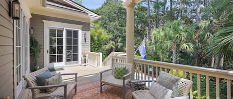 A covered porch with wicker furniture and a flag.