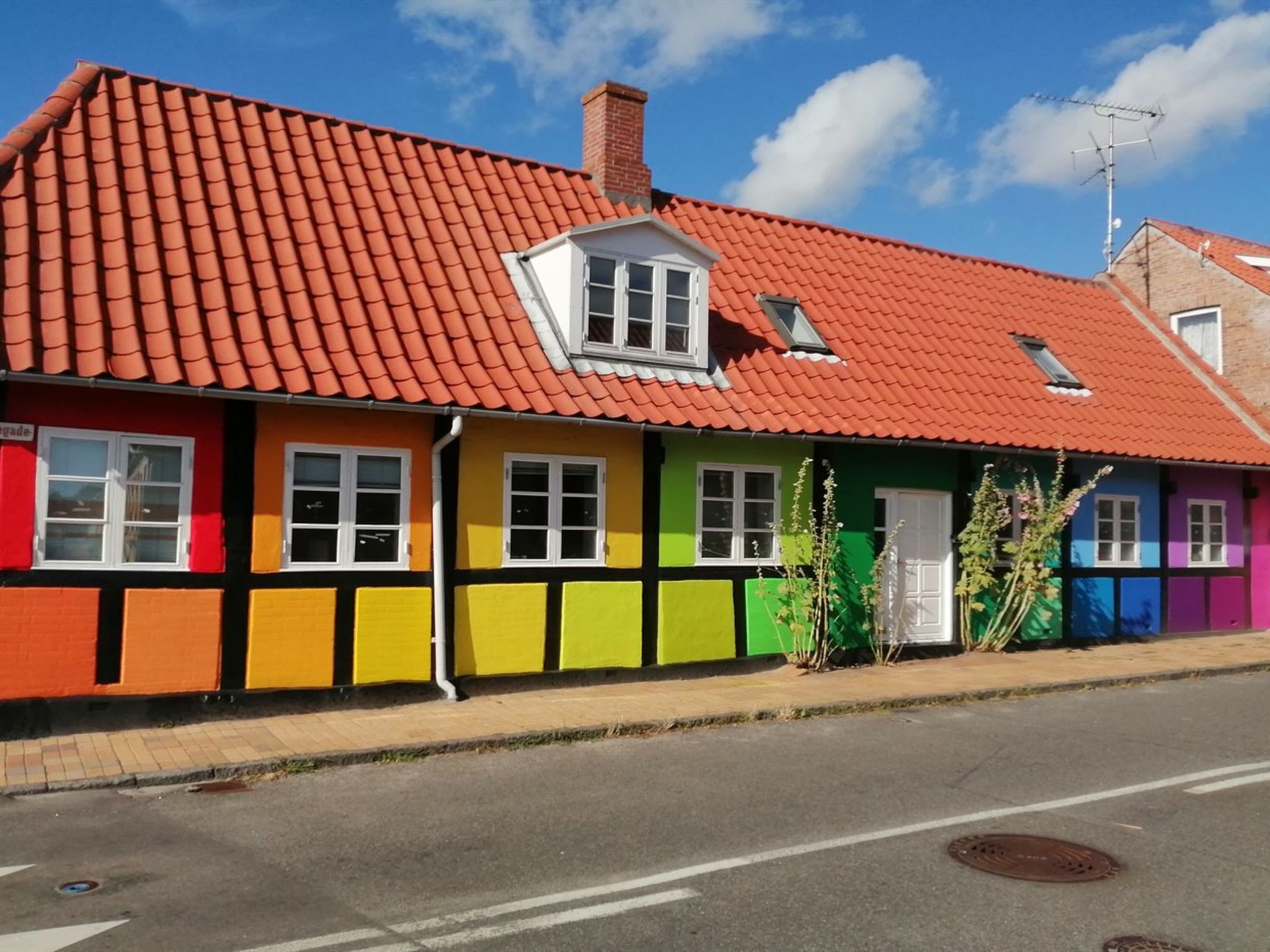 A row of colorful houses with red tiled roofs and a clear sky.