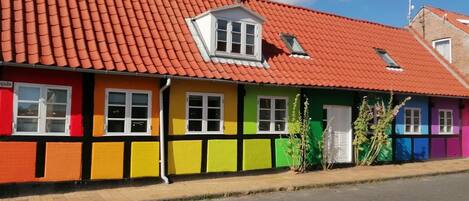 A row of colorful houses with red tiled roofs and a clear sky.