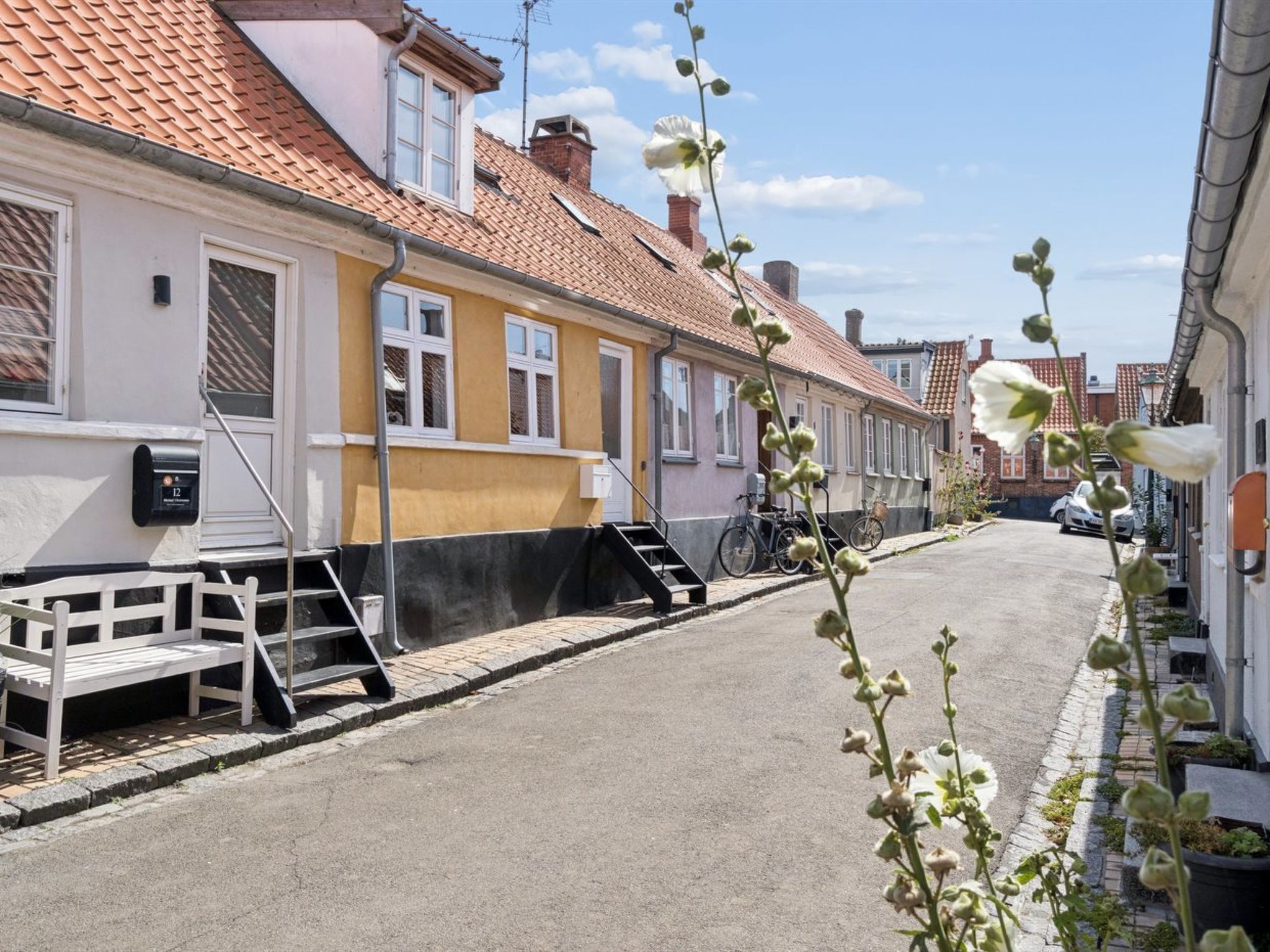 A narrow street with buildings on either side, a mailbox, and a bicycle.