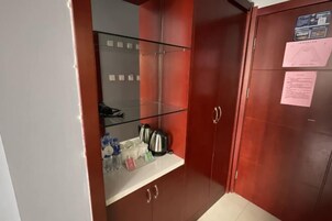 Una habitación con un armario de madera, un estante de vidrio con artículos de aseo y una puerta con un aviso.