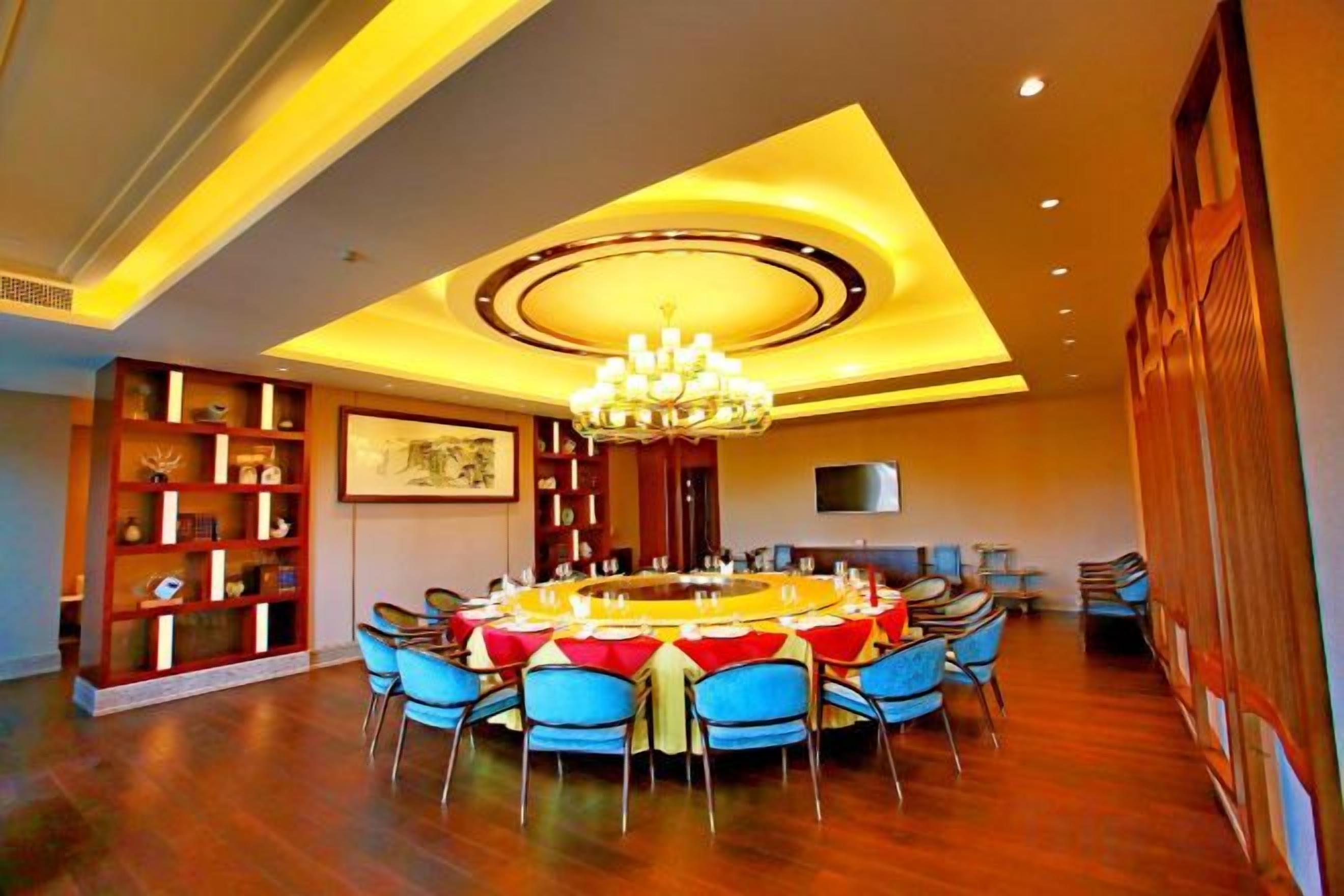 A dining area with a round table, blue chairs, and a chandelier.