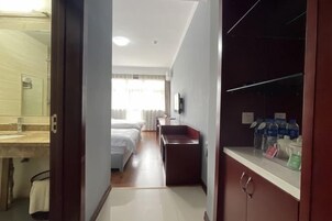 Una habitación de hotel con baño, cama, escritorio y armario.