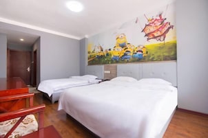 Habitación de hotel con dos camas, un escritorio rojo y un mural de Los Minions en la pared.
