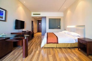 A hotel room with a bed, desk, television, and a view of the city. - Beidaihe Dongjinglu Hotel (Qinhuangdao)