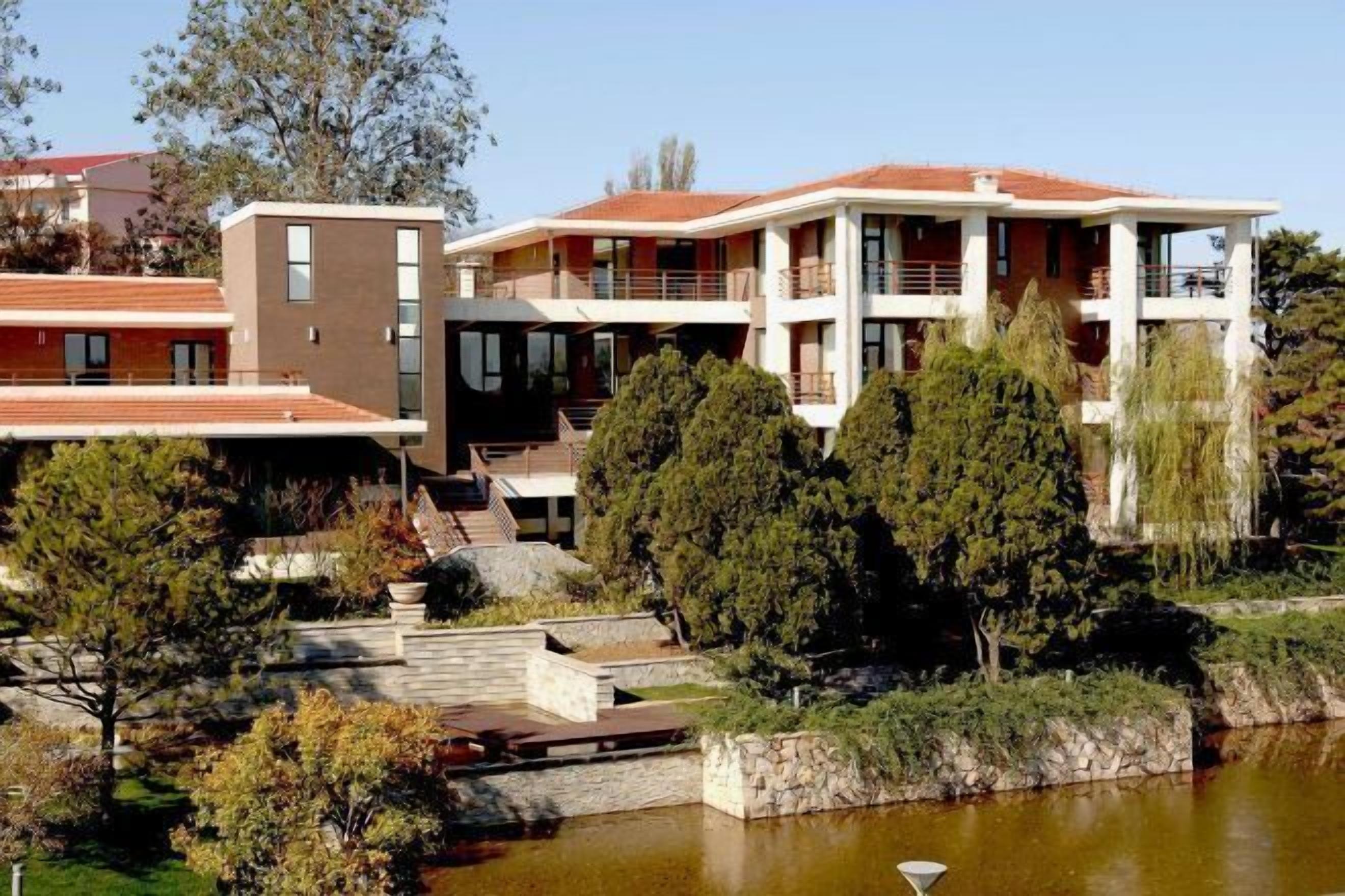 A multi-story residential building with a pool, surrounded by trees and vegetation.