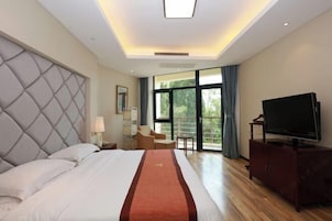 Habitación de hotel con una cama grande, televisión de pantalla plana, zona de estar y vistas al exterior.