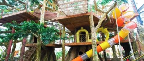 A treehouse play area with multiple levels, slides, and rope bridges.