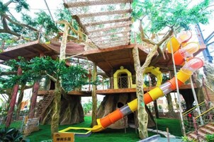 Un área de juegos en una casa del árbol con varios niveles, toboganes y puentes colgantes.