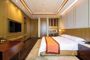 Une chambre d’hôtel dotée d’un grand lit, d’un téléviseur à écran plat, d’un bureau et d’un mini-bar.