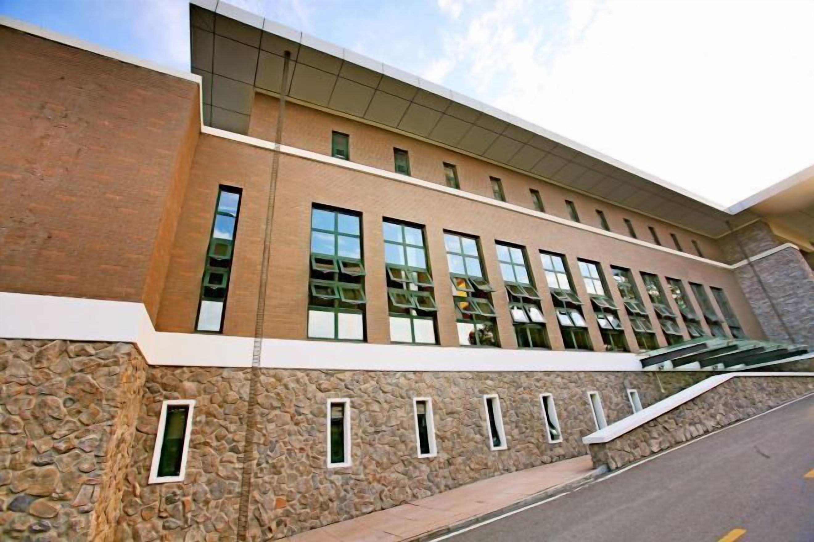 A modern building with a stone facade, multiple windows, and a flat roof.