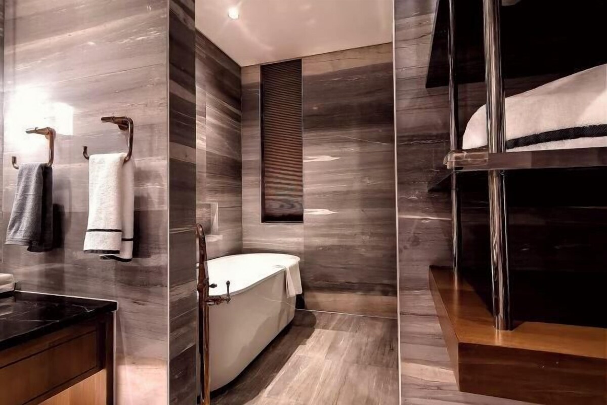 A modern bathroom with a bathtub, a vanity with a mirror, and towels on a rack.