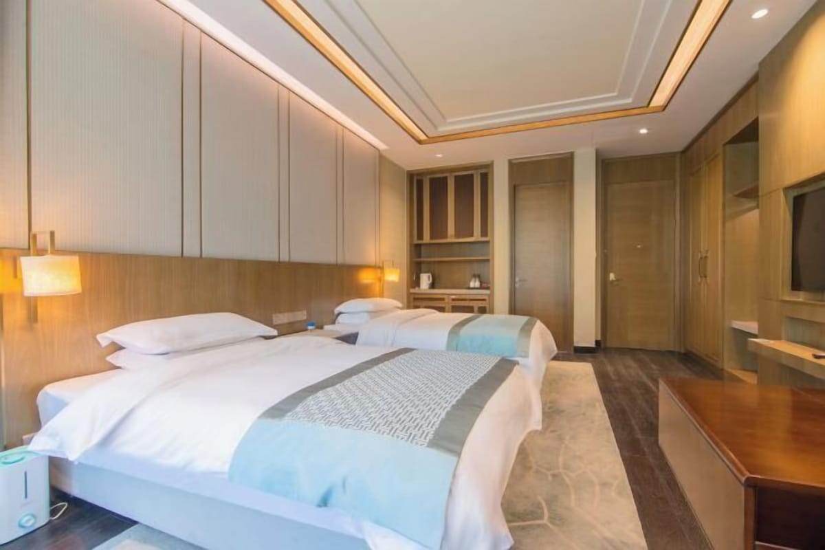 A hotel room with two beds, a desk, a TV, and a wardrobe.