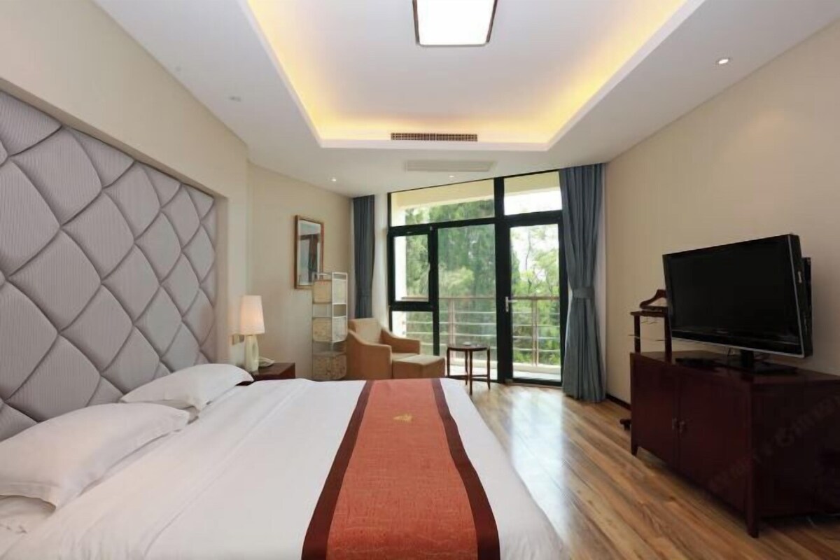 Habitación de hotel con una cama grande, televisión de pantalla plana, zona de estar y vistas al exterior.