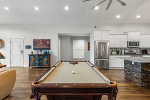 A modern living room with a pool table, a kitchen area, and a dining space. - Sedona retreat with 5 king bedrooms, pool, hot tub, and red rock views. (Sedona)