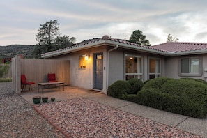 Ein Wohnhaus mit Terrasse, einer Tür und einem kleinen Garten.