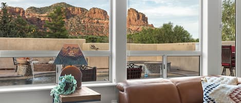 A room with a leather sofa, a table with a lamp, and a view of red rock formations.