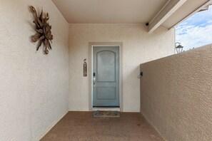 A door with a 'WELCOME' sign, a textured wall, and a decorative piece above it. - Sedona retreat with 5 king bedrooms, pool, hot tub, and red rock views. (Sedona)