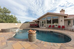 A swimming pool with a hot tub, surrounded by patio furniture and a house with large windows. - Sedona retreat with 5 king bedrooms, pool, hot tub, and red rock views. (Sedona)