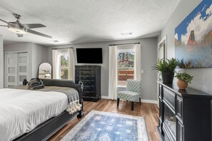 A bedroom with a bed, a dresser, a television, and a window. - Sedona retreat with 5 king bedrooms, pool, hot tub, and red rock views. (Sedona)