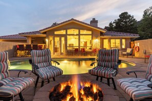 Ein Haus mit Pool, Sitzgelegenheiten im Freien und einem Feuerkorb.