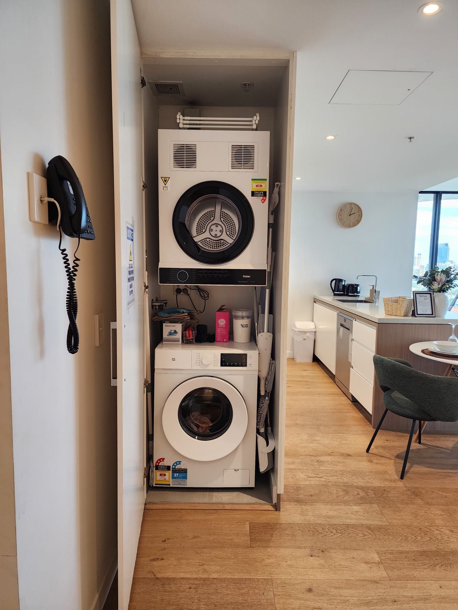 A compact laundry room with a washing machine, dryer, and a phone on the wall.