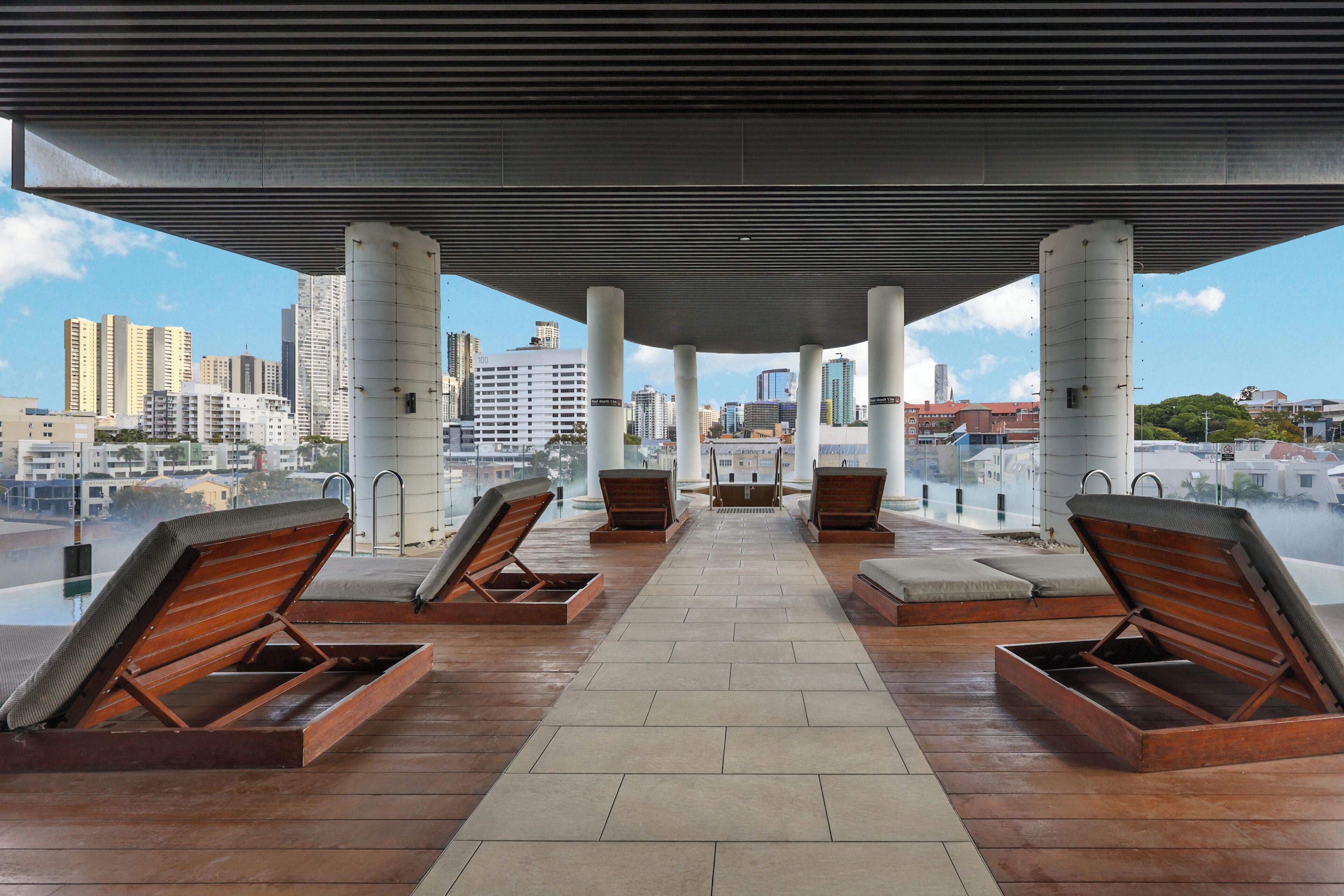 A rooftop terrace with sun loungers and a city view.